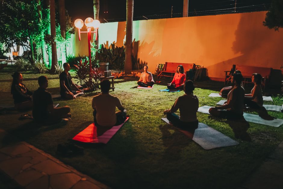 Group meditating in an outdoor yoga session at night, serene and peaceful atmosphere.