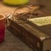A Biblia Sagrada with glasses rests on a table beside a red mug, symbolizing relaxation and reflection.