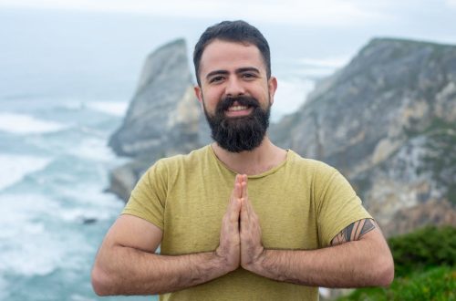 Portrait of a bearded man in a green shirt smiling by the cliffside in Portugal.