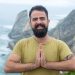 Portrait of a bearded man in a green shirt smiling by the cliffside in Portugal.