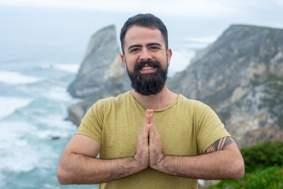 Portrait of a bearded man in a green shirt smiling by the cliffside in Portugal.