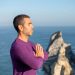 Side view of a man meditating by the ocean cliffs in Portugal, promoting relaxation and mindfulness.