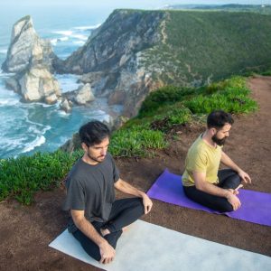Two men meditating on a scenic cliffside in Portugal. Serenity and nature combined.