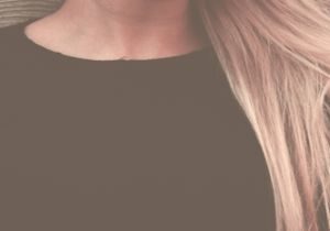 Close-up portrait of a woman with long, flowing blonde hair against a textured background.