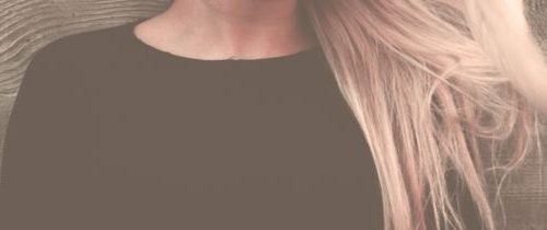 Close-up portrait of a woman with long, flowing blonde hair against a textured background.