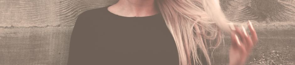 Close-up portrait of a woman with long, flowing blonde hair against a textured background.