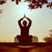 Silhouette of a person practicing yoga outdoors during sunrise, creating a calming atmosphere.