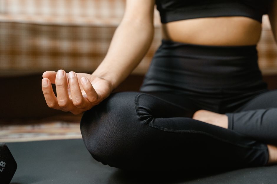 Close-up of a woman meditating in a yoga pose indoors, promoting mindfulness.