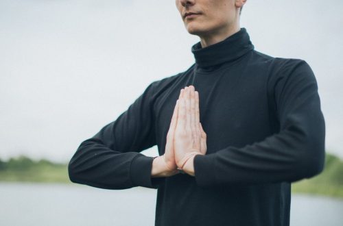 Close-up of a person meditating outdoors with hands in prayer position, promoting wellness.