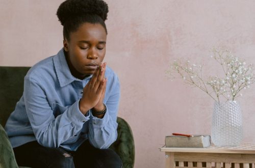 A woman in quiet contemplation, praying with hands clasped, embodying faith and serenity.