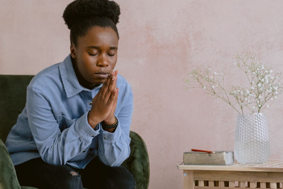 A woman in quiet contemplation, praying with hands clasped, embodying faith and serenity.