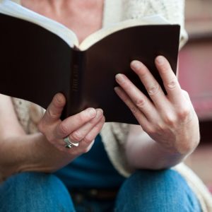 Hands holding an open Holy Bible, symbolizing faith and spirituality.