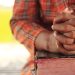 Close-up of clasped hands resting on a book outdoors, symbolizing prayer and reflection.