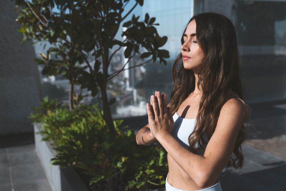 A woman practicing meditation outdoors under sunlight, embracing mindfulness and spiritual peace.