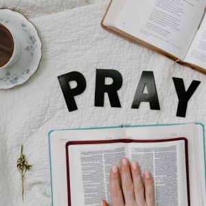Flat lay of morning prayer routine including Bible, coffee, and 'PRAY' letters.