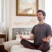Discover tranquility as a man meditates in a serene bedroom environment, capturing the essence of peace.