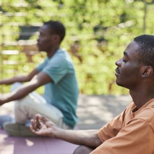 Two men meditating outdoors, capturing a sense of relaxation and mindfulness.