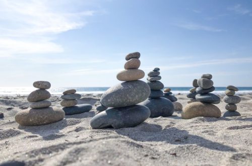 Stone towers on a sunlit beach, capturing tranquility and nature's balance.