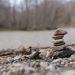 A stack of stones beautifully balanced on a rocky riverbank with a blurred forest background.