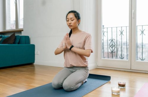 A woman practicing meditation and relaxation indoors on a yoga mat, promoting a healthy lifestyle.