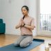 A woman practicing meditation and relaxation indoors on a yoga mat, promoting a healthy lifestyle.