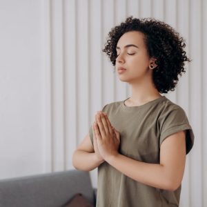 Young woman meditating indoors, practicing mindfulness and relaxation. Peaceful and serene atmosphere.