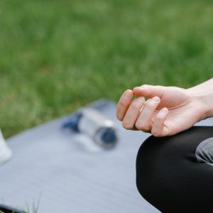 Close-up of a woman meditating outdoors on a mat. Focus on tranquility and mindfulness.