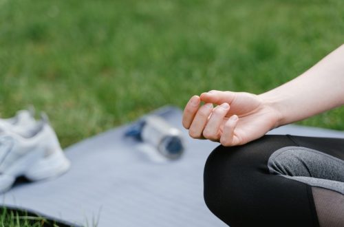 Close-up of a woman meditating outdoors on a mat. Focus on tranquility and mindfulness.