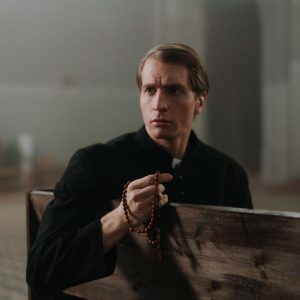 A priest holding rosary beads, seated in a church pew, embodying spirituality and tranquility.