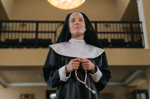 Nun in a church praying with a rosary, embodying religion and devotion.