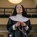 Nun in a church praying with a rosary, embodying religion and devotion.