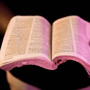 An open Bible held in hands with dramatic lighting, creating a serene atmosphere.
