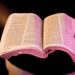 An open Bible held in hands with dramatic lighting, creating a serene atmosphere.