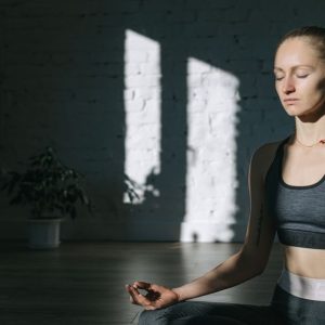 A woman meditates indoors in a serene yoga session, embracing mindfulness and tranquility.