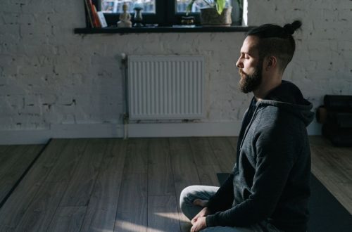 Side view of a man meditating indoors in a serene environment, promoting mental wellness and tranquility.
