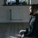 Side view of a man meditating indoors in a serene environment, promoting mental wellness and tranquility.