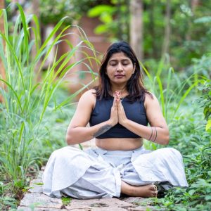 Woman meditating in lush garden setting, finding inner peace.