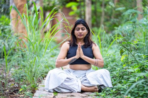 Woman meditating in lush garden setting, finding inner peace.