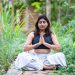 Woman meditating in lush garden setting, finding inner peace.