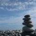 A tranquil scene of a balanced stone stack on a pebble beach under a bright blue sky.