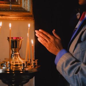 A person praying beside lit candles in a religious setting, evoking peace and spirituality.