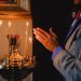 A person praying beside lit candles in a religious setting, evoking peace and spirituality.