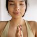 A peaceful woman meditating with closed eyes in a yoga pose, embracing mindfulness indoors.