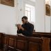 African American priest in deep prayer at a serene church setting.