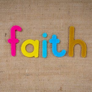 Brightly colored text spelling 'faith' on a textured burlap material, conveying spirituality and belief.