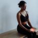 A woman in black activewear meditates with a candle, seated indoors for mindfulness and relaxation.