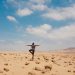 A man balancing in a serene yoga pose amidst the vast desert landscape of Huacachina, Peru.