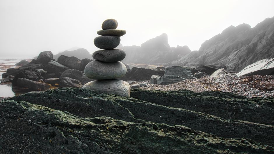 Stacked stones on a foggy rocky beach creating a tranquil scene.