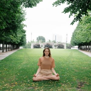 Woman practicing yoga meditation in a peaceful green park setting