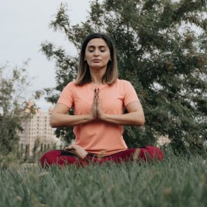 Woman practicing yoga and meditation in park. Enhancing mindfulness and relaxation outdoors.